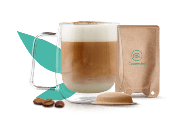 tazza con cappuccino accanto a una capsula e a una bustina a base carta