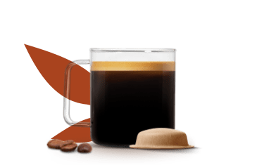 tazza piena di caffè preparato accanto a una capsula a base carta