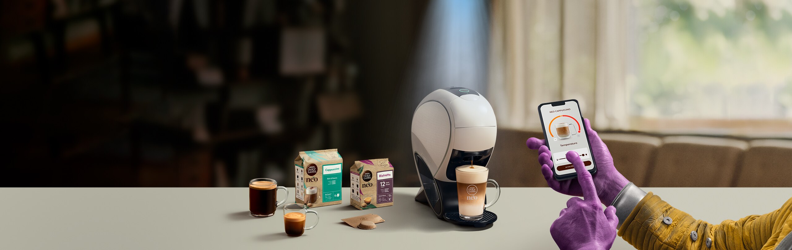 Una mano aliena che usa l'app NESCAFÉ Dolce Gusto per personalizzare un caffè. Macchina da caffè NEO Latte, confezione di caffè e bevande.